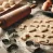 DALL·E 2024-11-05 20.21.21 - A detailed image showing the process of making dog treats. The scene includes a rolling pin, cookie cutters in bone and heart shapes, and dough rolled